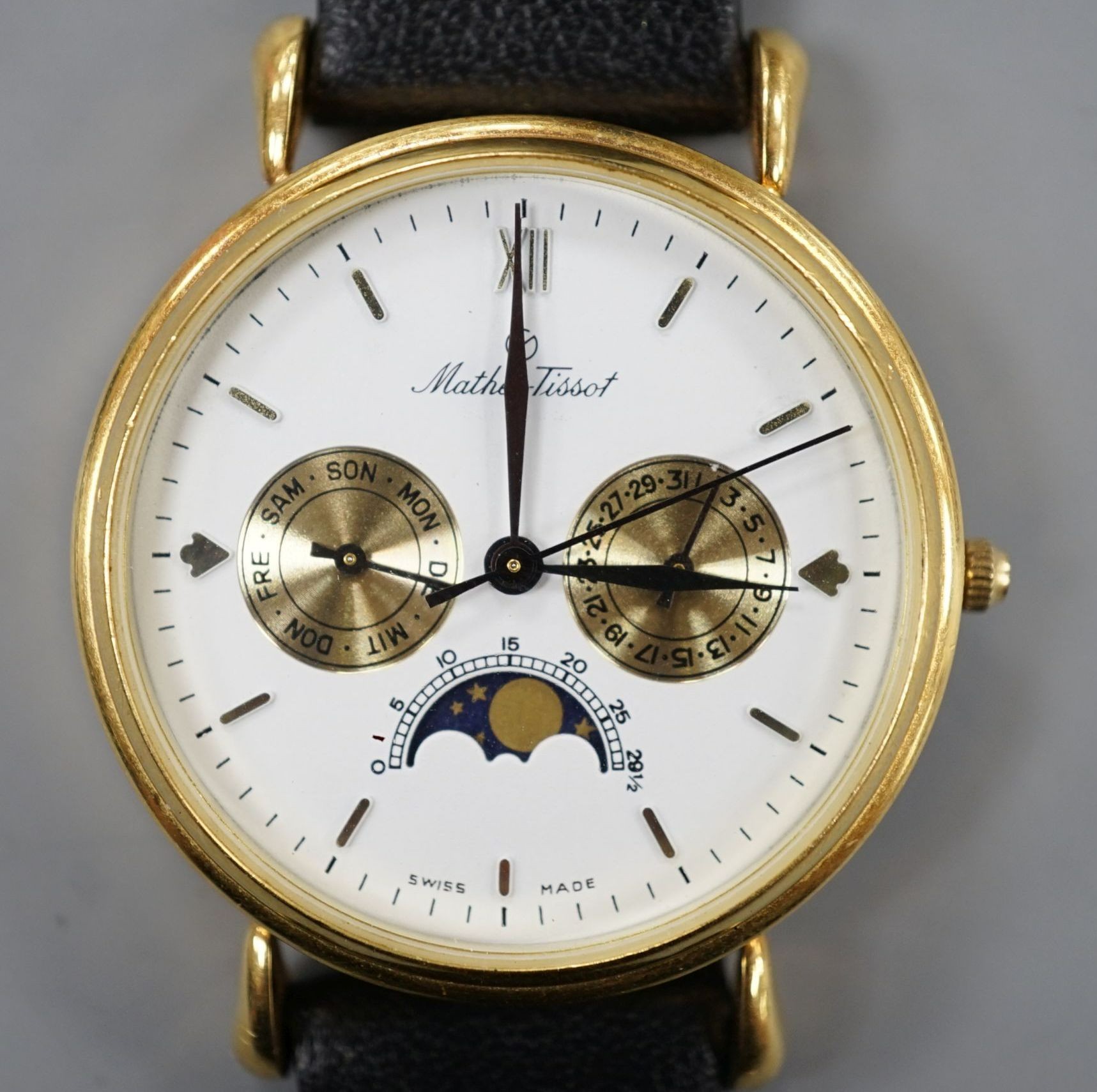 A modern 18k Mathey-Tissot calendar moonphase quartz wrist watch, on a black leather strap, no box or papers.